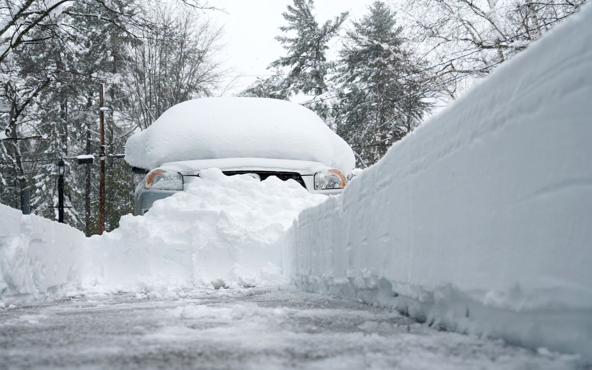 snow covered car after blizzard with snow removed driveway by snow blower