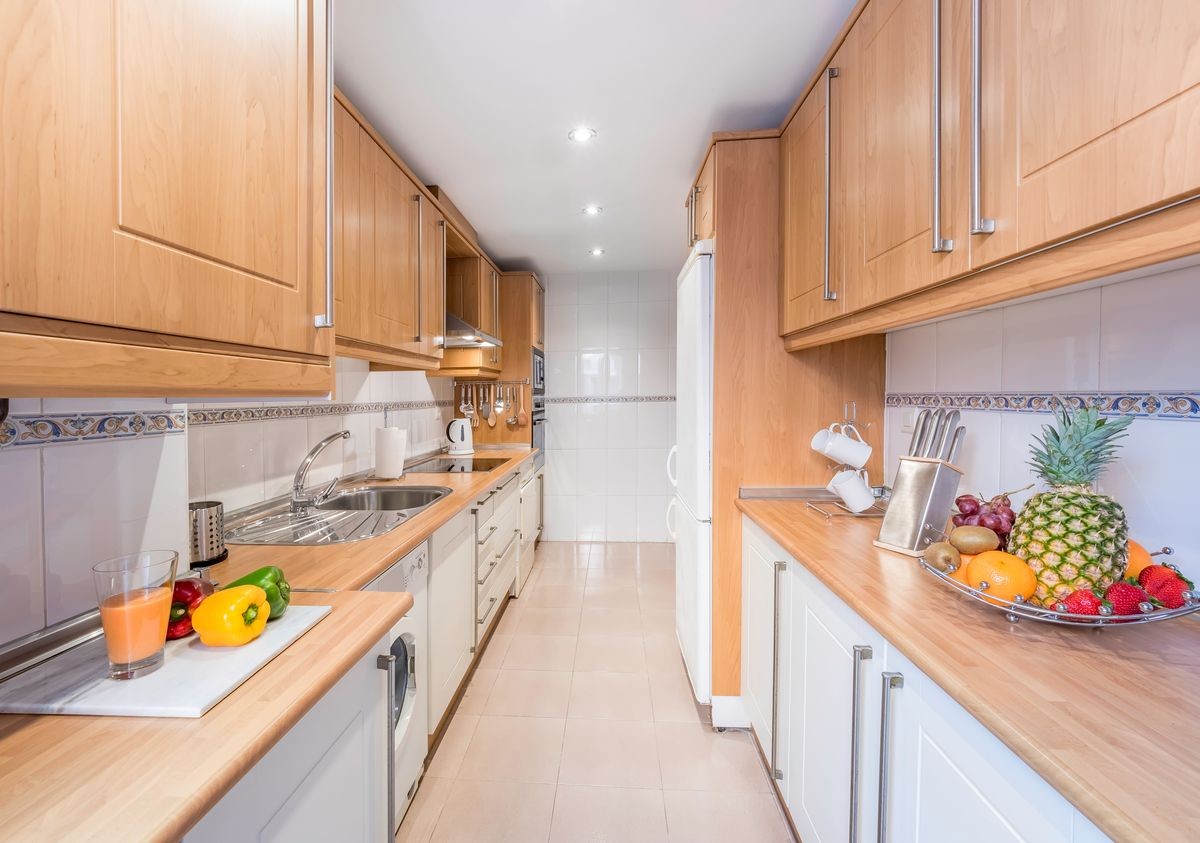 New stylish bright kitchen with wooden cabinets. Spacious modern fully equipped appliance interior with wooden desk, ceramic stove and  big windows